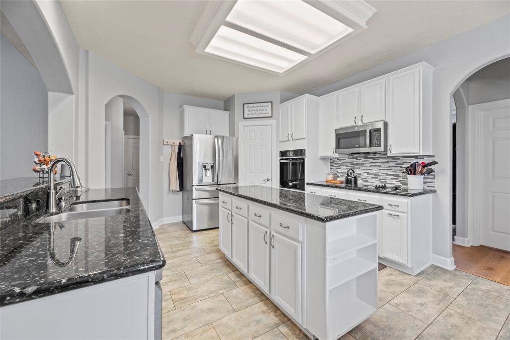 This chef's island kitchen is designed to impress, with granite countertops, crisp white cabinetry with oversized drawers and open shelving, plus two spacious walk-in pantries. With plenty of room for all your favorite kitchen essentials, it’s the perfect space to create and entertain.