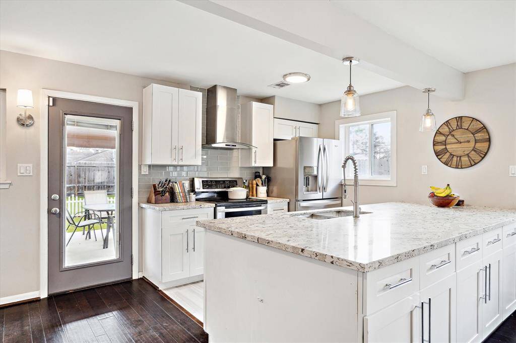 Kitchen boasts access to the covered outdoor living and is complete with granite countertops, stainless steel appliances, and gorgeous subway tile backsplash. Note the abundance of storage below the peninsula island.