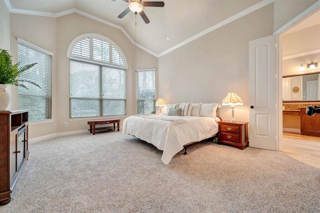 This spacious primary bedroom features abundant natural light through large arched windows and elegant soaring ceilings with gorgeous views of the private backyard oasis.
