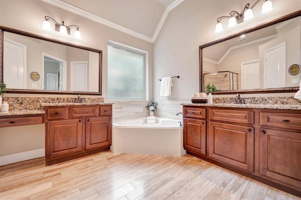 This bathroom features a spacious layout, abundant natural light, and elegant vanity cabinets with a jetted tub and separate shower.