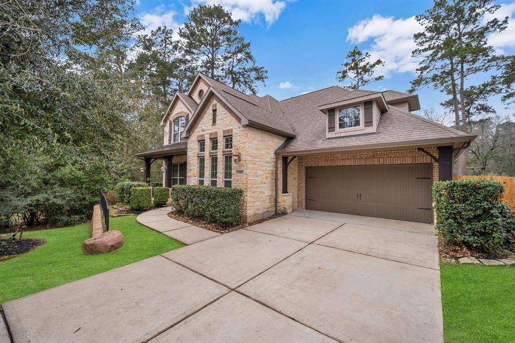 This home features a spacious exterior with a brick and stone facade, a covered porch, and lush landscaping surrounding the property.
