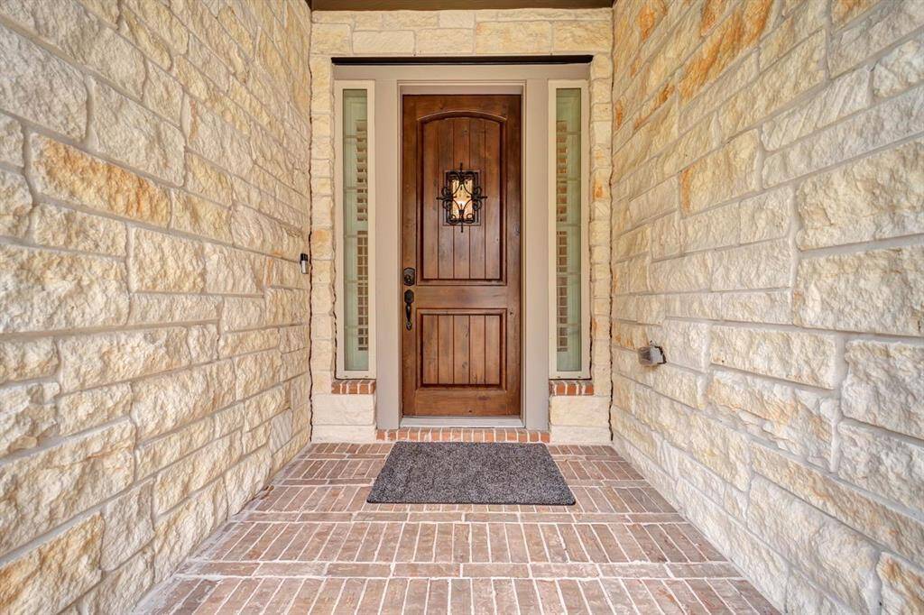 Step up to this beautiful entry surrounded by rock with a brick walkway.
