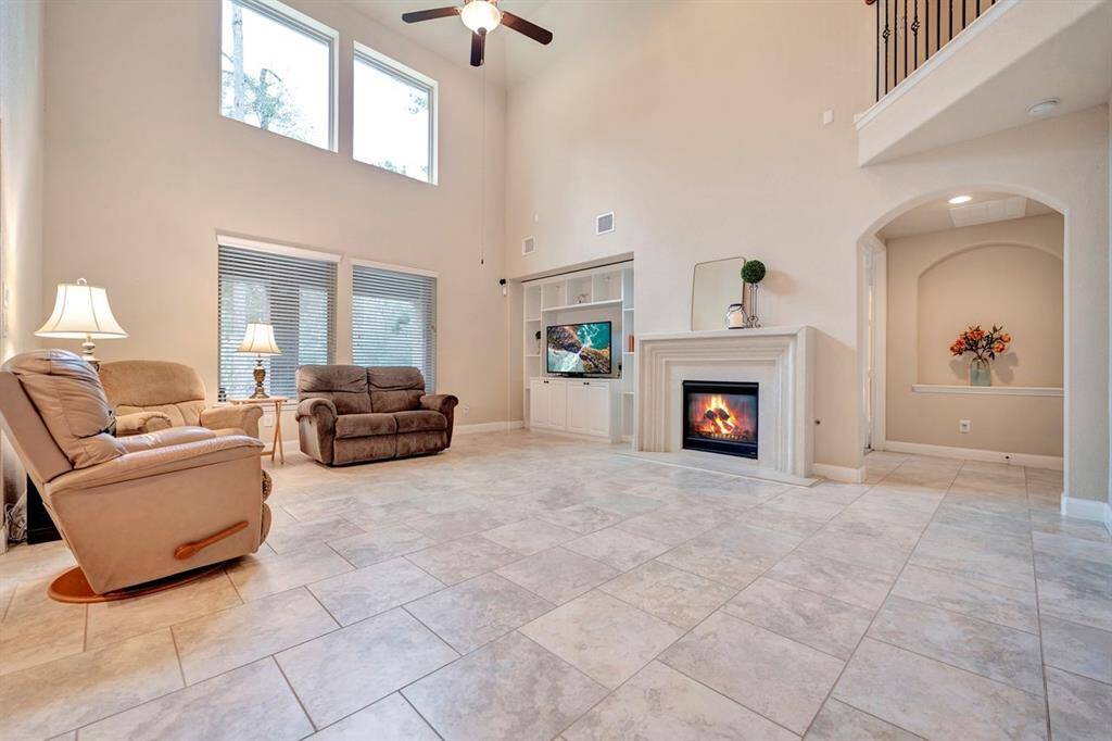 This home features a spacious layout, abundant natural light, an elegant fireplace, built-ins, and ceramic tile flooring.
