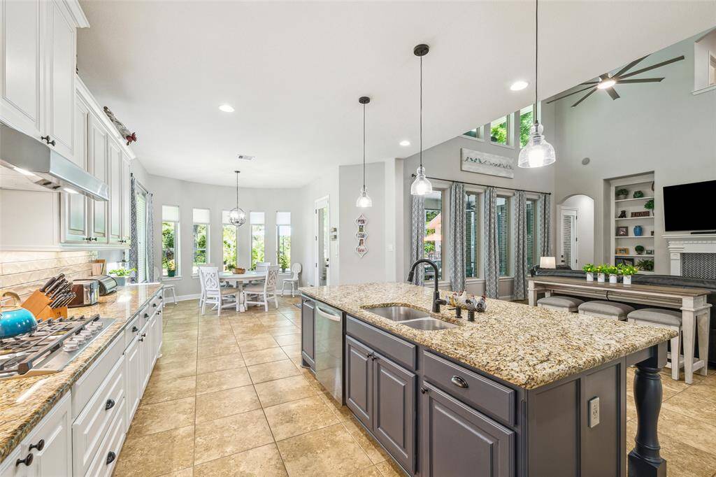 Open plan kitchen and living space with neutral colors, high ceiling, tiled floors, and a mix of classic and contemporary design elements.