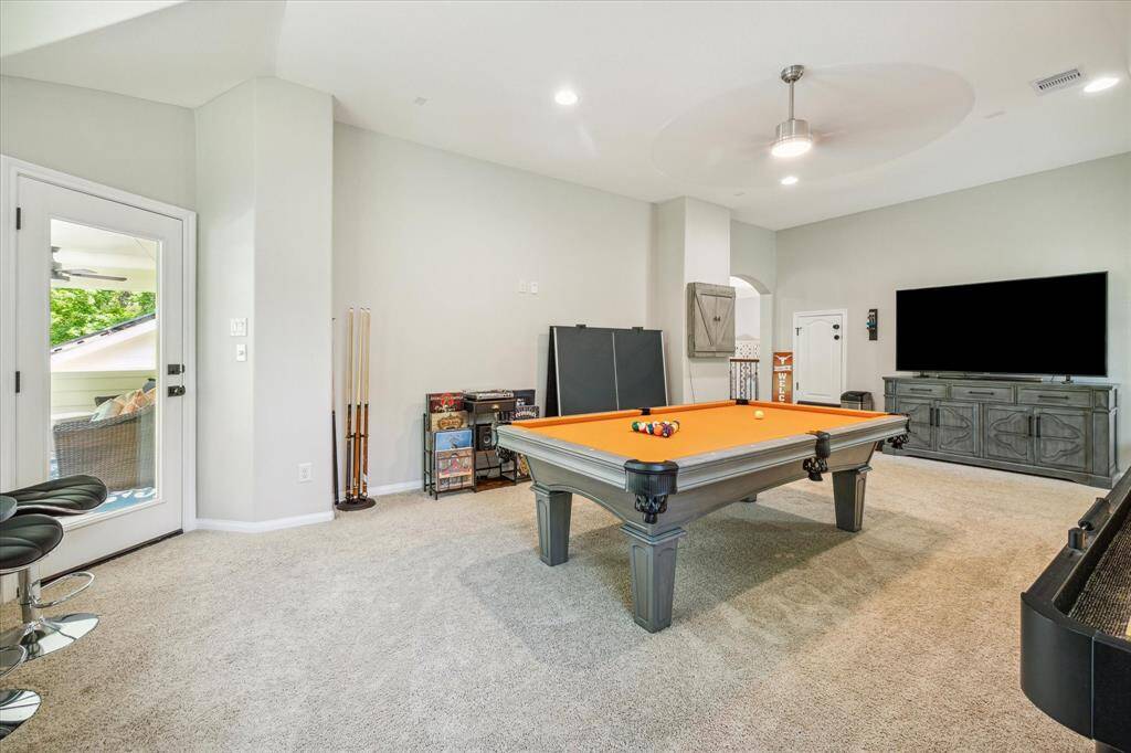 Game room with door leading to spacious covered balcony overlooking pool area