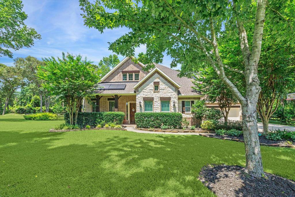 Coventry house with brick and stone facade, lush green lawn, and mature trees.