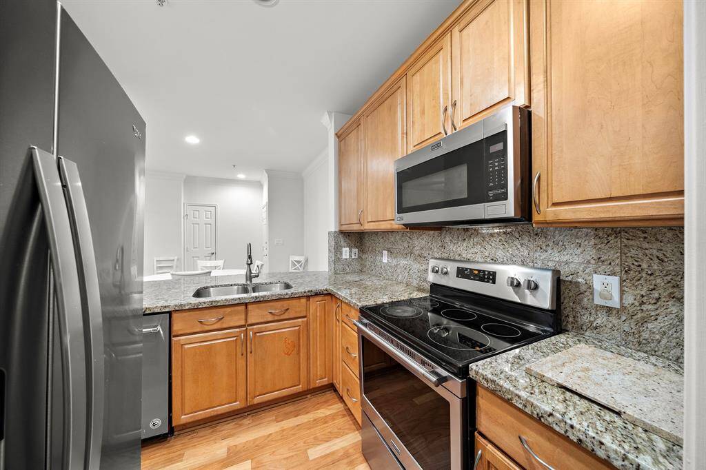 Outfitted with modern stainless steel appliances, including a built-in microwave and electric range, this kitchen is both functional and stylish.