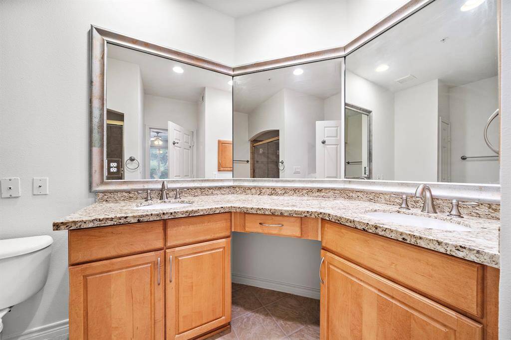 The primary bathroom boasts dual sinks, a large mirror, and elegant granite countertops, creating a spa-like atmosphere.