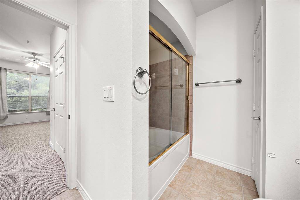 The shower/ tub combo in the primary bath is finished with stylish tile, offering a refreshing retreat at the end of the day.