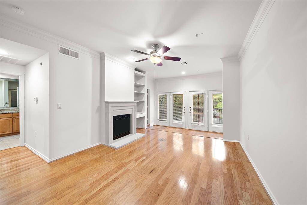 This expansive living room offers gleaming hardwood floors, built-in shelving, and a cozy fireplace, perfect for relaxing evenings at home.