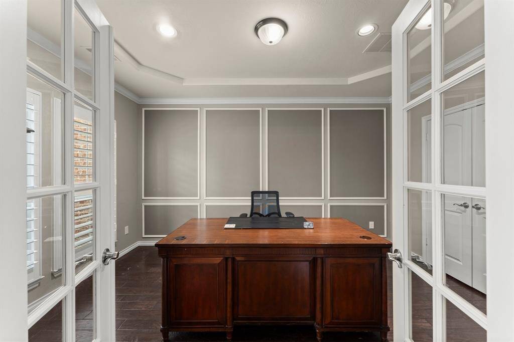 Tucked behind glass double doors is the private home office with a large storage closet.