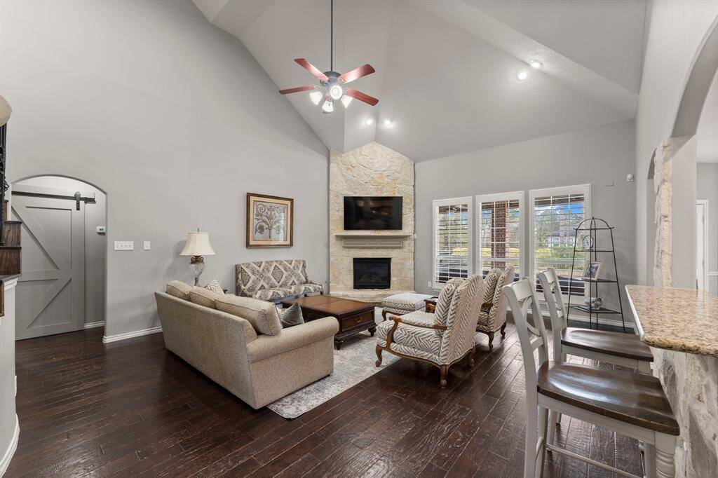 Enter the 2-story living room featuring a ton of natural light from the wall of windows and a stone fireplace.