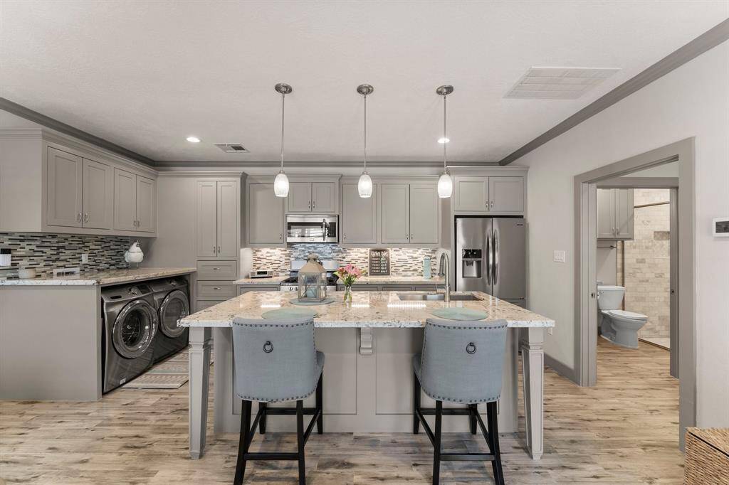 A well-planned one bedroom Guest Home with a full kitchen, bar seating, living room, laundry area, and full bathroom with a walk in shower.