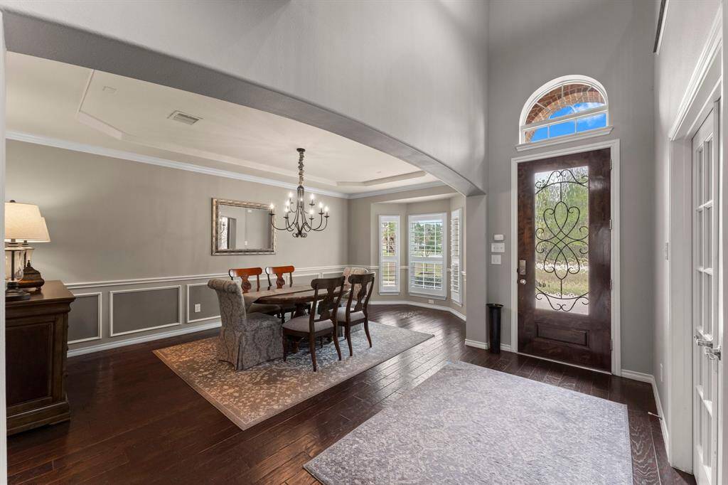 Spacious formal dining room features a tray ceiling and view of the front lawn.