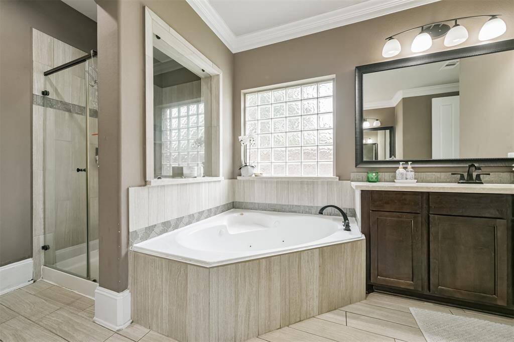 Primary En-Suite Bath Features Dual Vanities, Walk-In Shower, Soaking Tub, Framed Mirrors and a Walk-In Closet