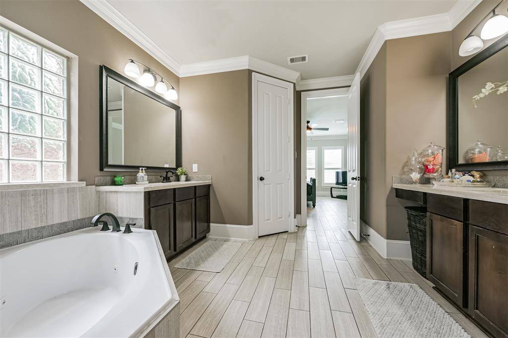 Primary En-Suite Bath Features Dual Vanities, Walk-In Shower, Soaking Tub, Framed Mirrors and a Walk-In Closet