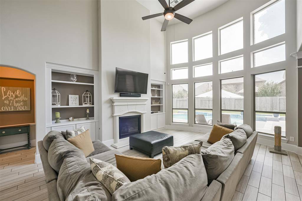 Living Room Features Soaring Ceilings, A Wall of Windows Illuminating the Home with Morning Light, Built-In Cabinetry and a Fireplace
