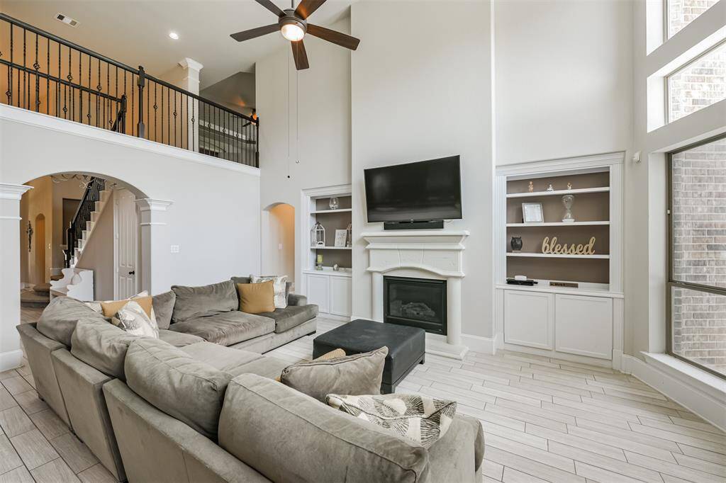 Living Room Features Soaring Ceilings, A Wall of Windows Illuminating the Home with Morning Light, Built-In Cabinetry and a Fireplace