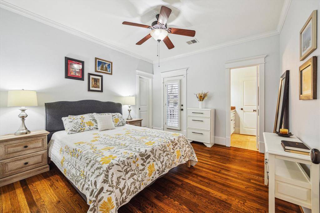 Secondary bedroom with porch access, hardwood floors, crown molding, plantation shutters, walk-in closet and direct access to a bathroom.