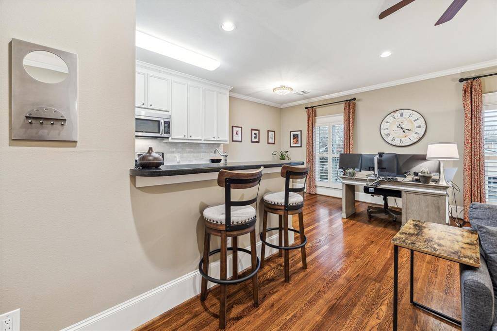View of the breakfast bar and dining area. Two large windows allow natural light into the room.