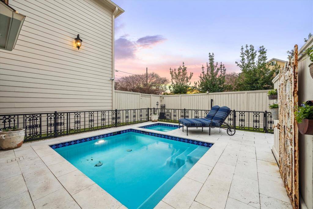 Picture making lasting memories while swimming in the pool or unwinding in the hot tub. The pool is beautifully enclosed by an iron fence, adding both style and security.