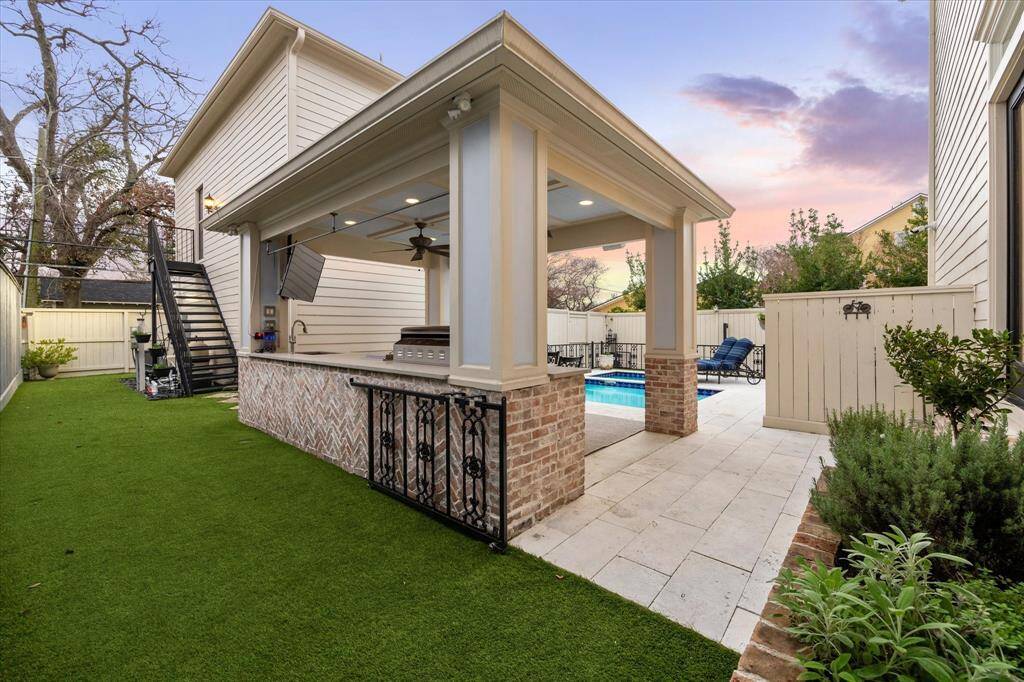 View of the back of the out door kitchen and additional turf for your loved ones to run and play.