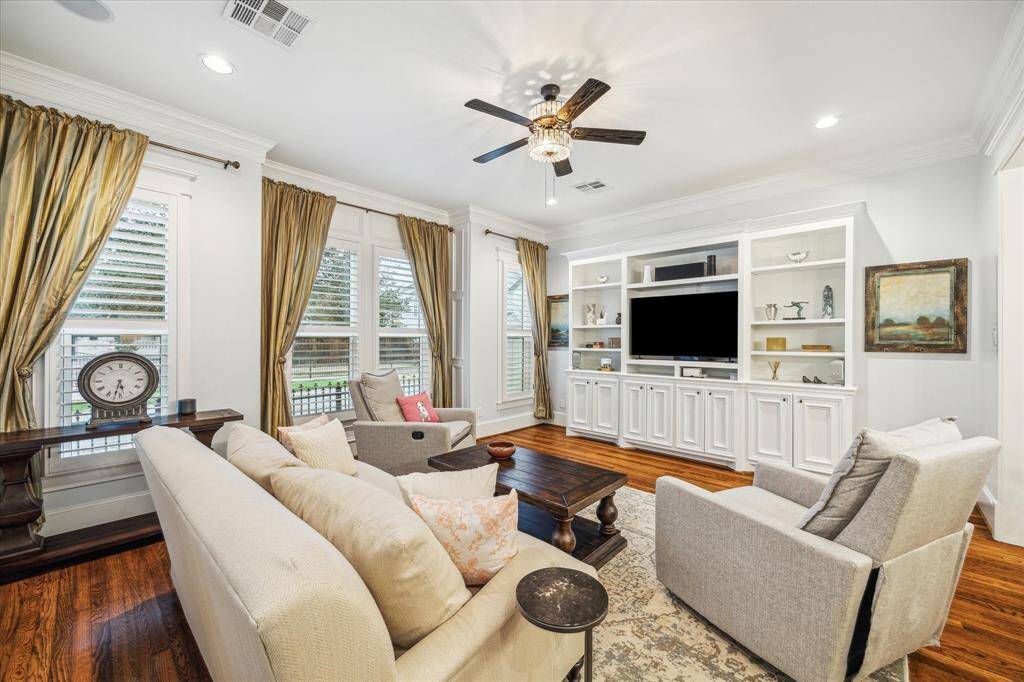 The living room also boasts built-ins, surround sound, hardwood floors, plantation shutters, recessed lighting, and a stylish ceiling fan.