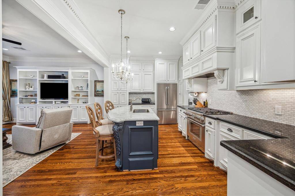 Additional kitchen features include a luxurious marble island with a breakfast bar, beautifully accented by two chandelier pendants. The space also boasts an appliance garage for clutter-free countertops, under cabinet lighting and a roomy walk-in pantry for seamless organization.