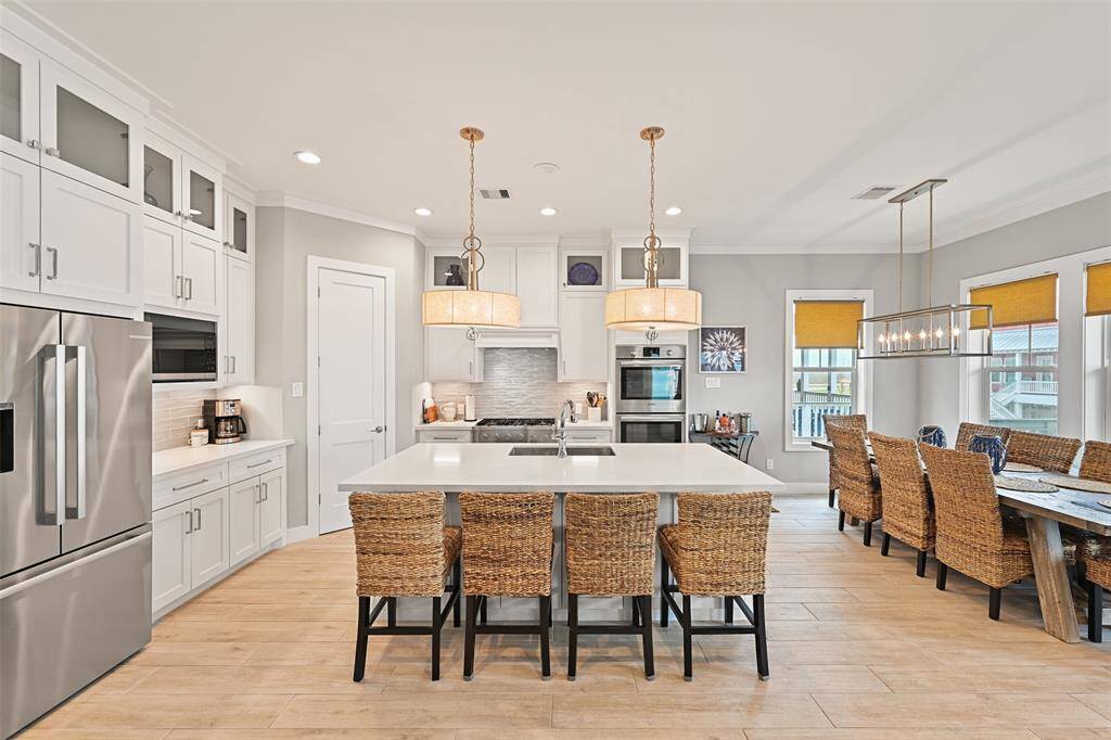 Functional and stylish, this large island provides additional seating and prep space.  This angle offers a look at the extra storage in the front of the isalnd.  The Bosch appliance package with double oven, dishwasher and refrigertor.  The lighting is the cherry on top!