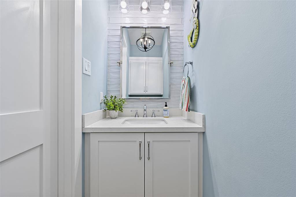 This powder room continues the stylish tile work behind the mirror, from the vanity to the ceiling, modern fixtures and clean aesthetic.  This services the downstairs living area.