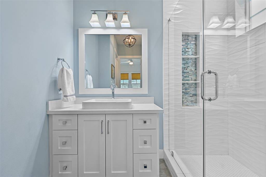 A closer look at the first floor bedroom ensuite. Relax and enjoy the glass-enclosed spa-like shower, custom cabinetry and modern fixtures and floor to ceiling tile in the shower..