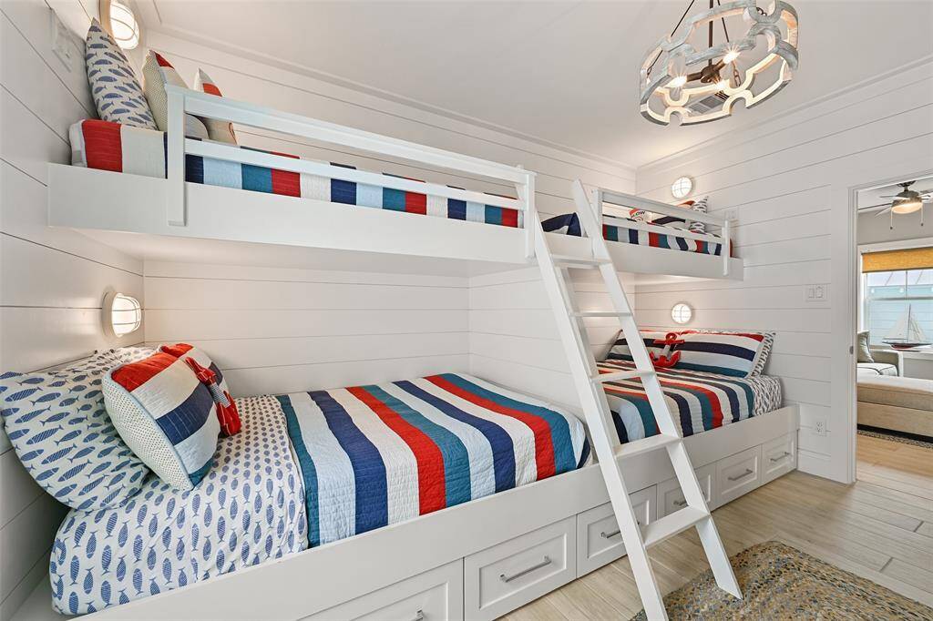 This custom bunk room offers twin meds over full beds, comfortably sleeping 6! Perfect for accommodating the kids or additional guests.  Notice the shiplap detail on the walls and all of the extra storage underneath the built in bunks.