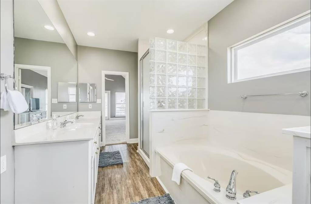 The primary bedroom with dual sinks, a soaker tub, and a separate shower.