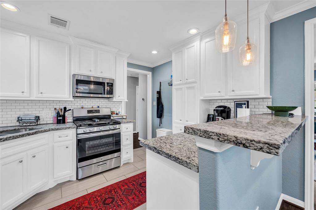 The kitchen features modern white cabinetry, granite countertops, and a subway tile backsplash.
