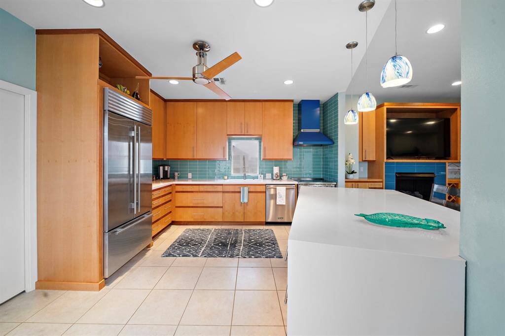 Sleek kitchen remodel in 2022 includes quartz waterfall countertops and glass tile backsplash. Built in Subzero refrigerator.