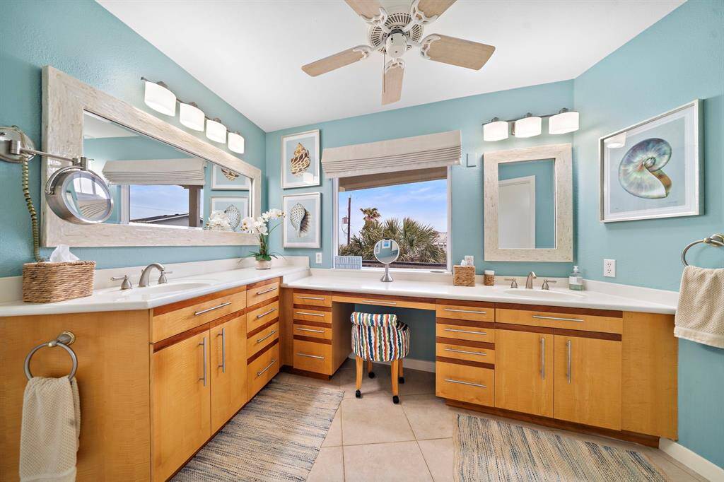Dual primary vanities with seated vanity and remote controlled custom blind.