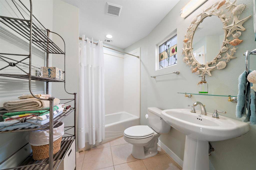 Guest bathroom with direct access to a guest bedroom and hallway.  Tub/shower and vanity.  Note the stained glass window.