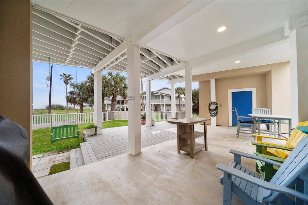 Expansive outdoor entertaining space, complete with swing, dining table and chairs, and polywood bar.  (Colored adirondack chairs are excluded).  Blue door is a storage closet.