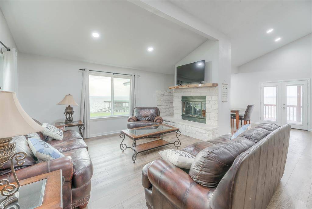 Living area with white stone fireplace to relax and enjoy a movie by the fire along with a gorgeous view of the lake