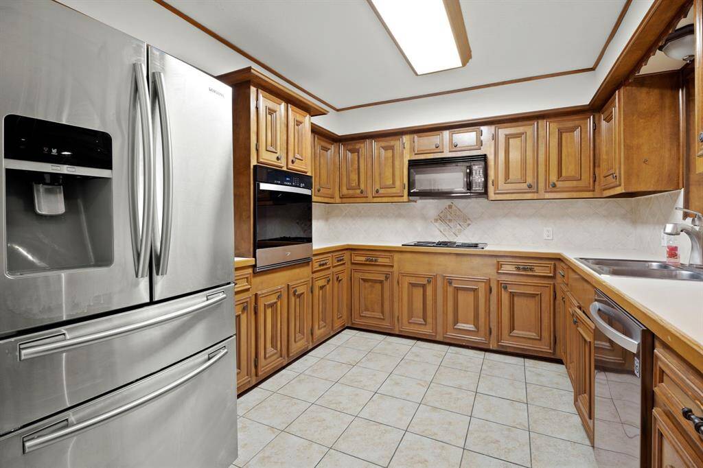 The kitchen is equipped with a built-in oven, a microwave, a dishwasher, a countertop stove, and double sinks.