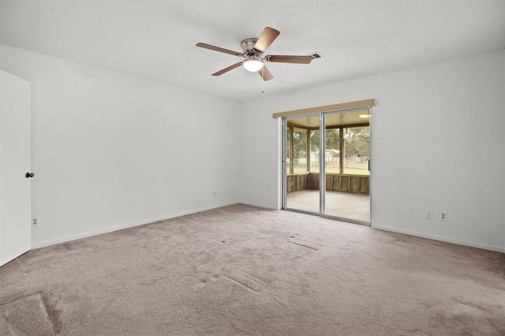 The primary bedroom features a sliding glass door that opens to the back covered patio, includes dual closets, and is accompanied by a private ensuite bathroom.