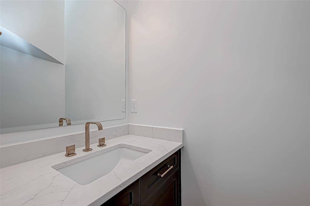 This photo showcases a modern bathroom vanity with a sleek marble countertop, an undermount sink, and a large mirror. The faucet and handles are in a stylish metallic finish, complementing the clean, minimalist design.