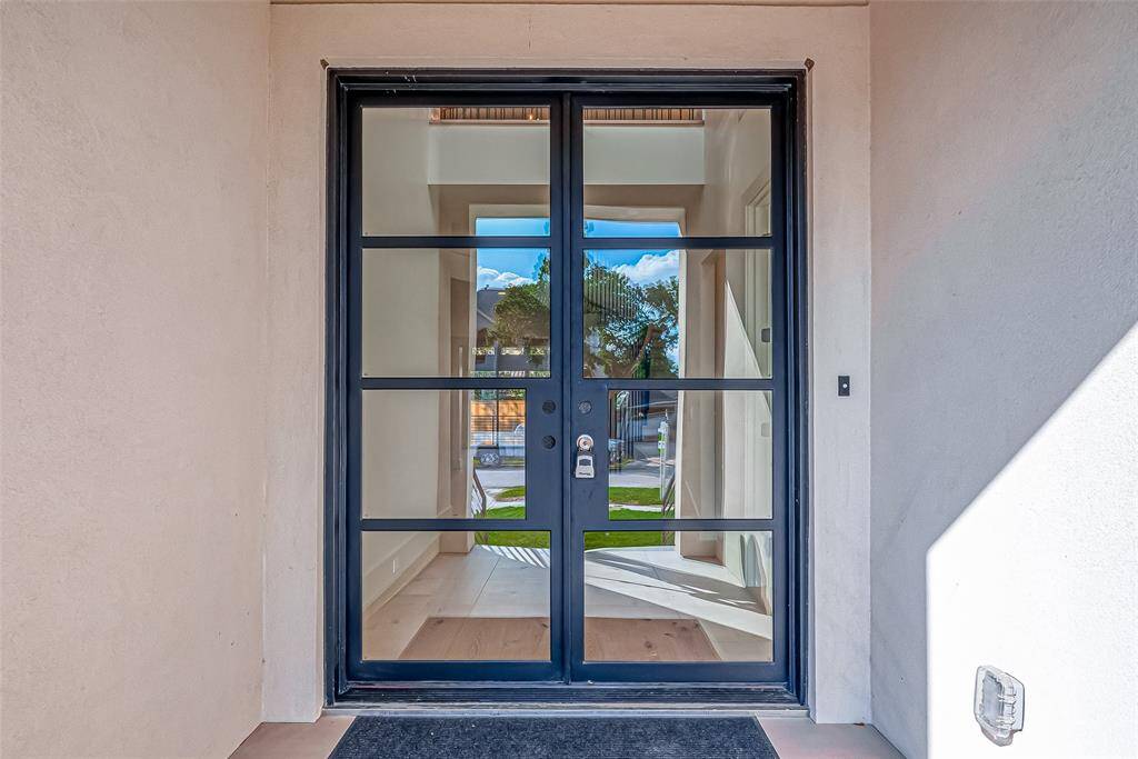 This photo shows a modern entryway with a sleek black-framed glass door, providing a welcoming and stylish entrance that allows natural light to illuminate the interior.