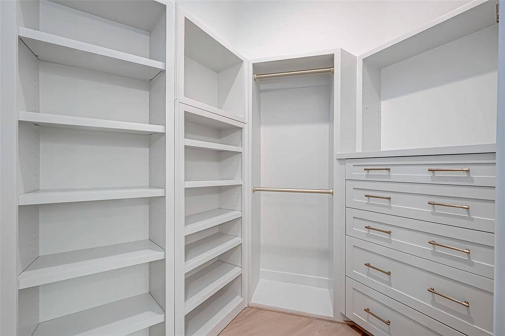 Spacious walk-in closet with ample shelving, hanging space, and a set of drawers featuring sleek, modern handles. Ideal for organized storage and accessibility.