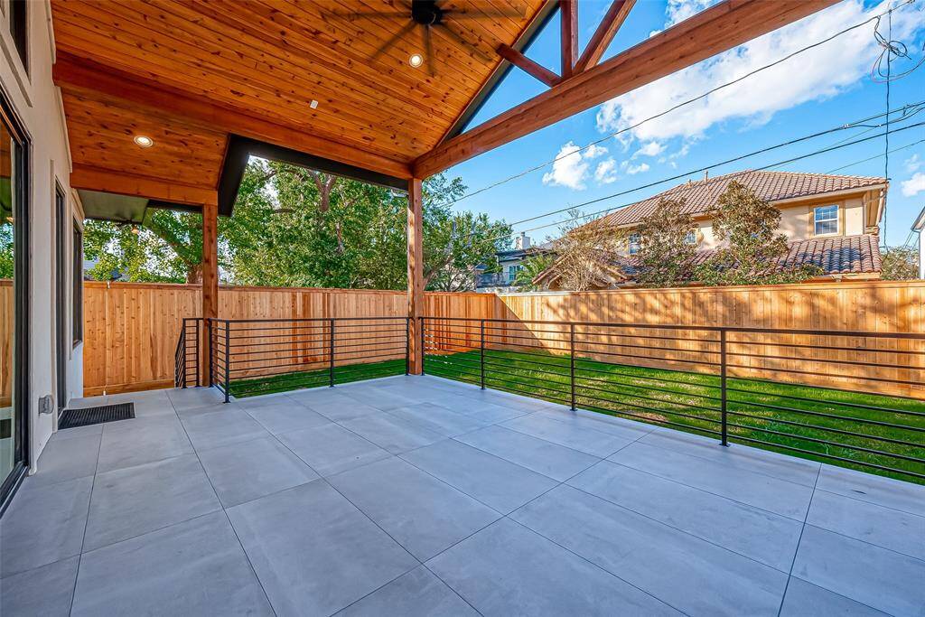 This photo showcases a spacious covered patio with a wood-paneled ceiling and a ceiling fan. It overlooks a well-maintained backyard with a wooden privacy fence, offering a great space for outdoor relaxation and entertaining.
