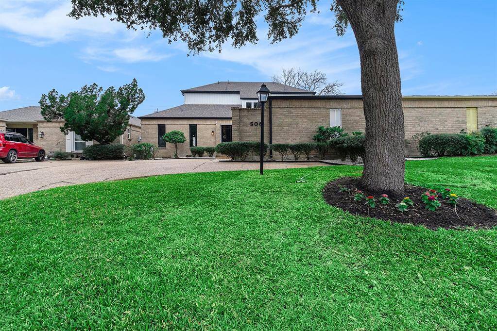 This photo showcases a single-story brick home with a well-maintained front yard. The property features mature trees and manicured shrubs, providing an inviting and serene atmosphere. A driveway leads to the entrance, enhancing accessibility and curb appeal.