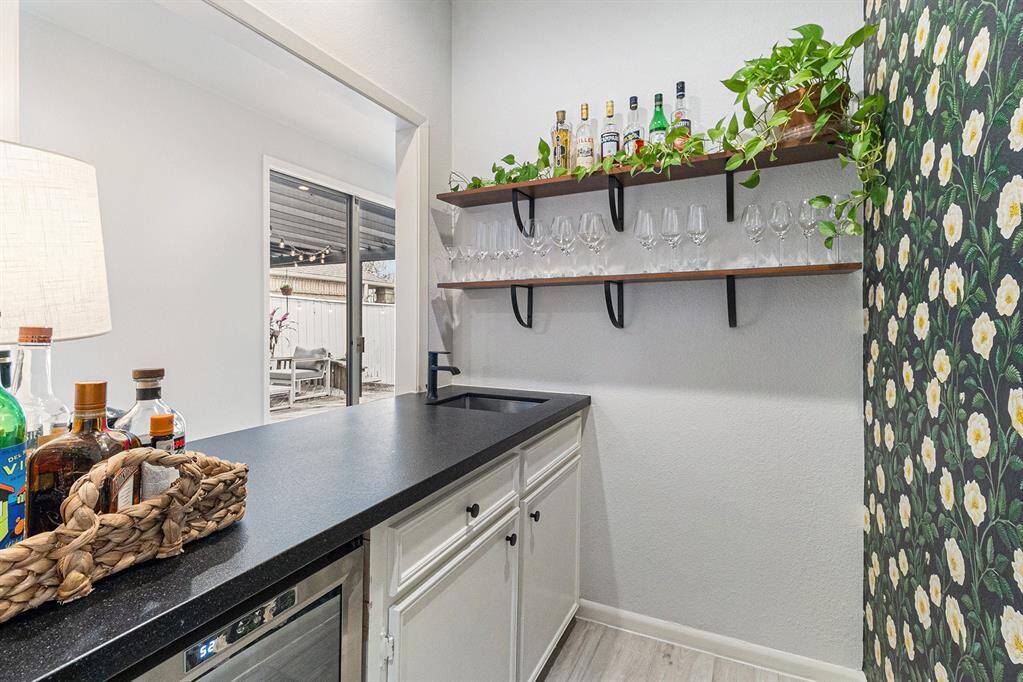 Wet bar with wine fridge and designer wall paper is close to the living areas and kitchen.