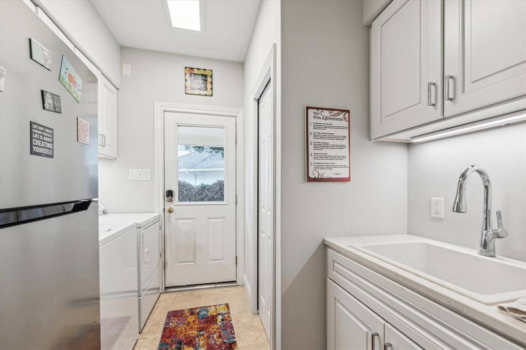 UTILITY ROOM- Room for refrigerator, sink and behind the pocket door is another powder bathroom with easy access to backyard.