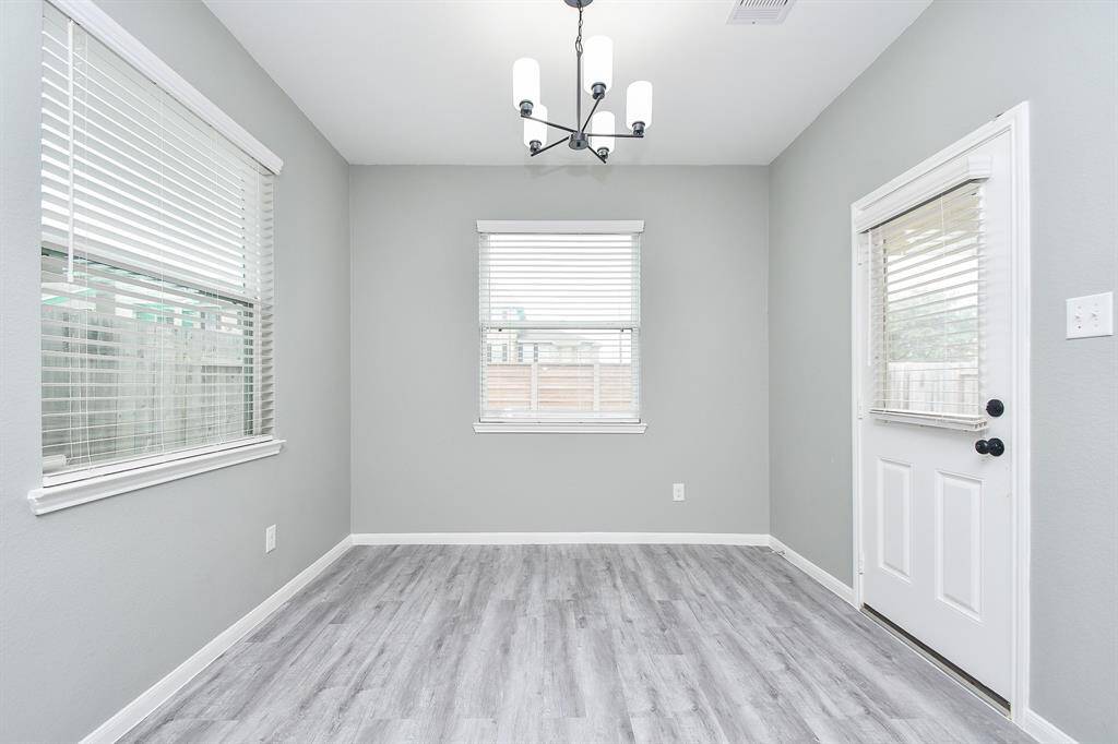Nestled beside the kitchen, the dining area enjoys an abundance of natural light from large windows and a glass-paneled door leading outside.