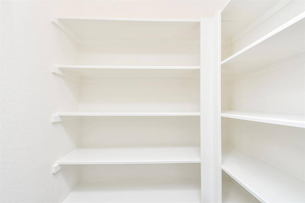 This neatly arranged pantry offers plenty of shelving for storing everything from dry goods to kitchen essentials.